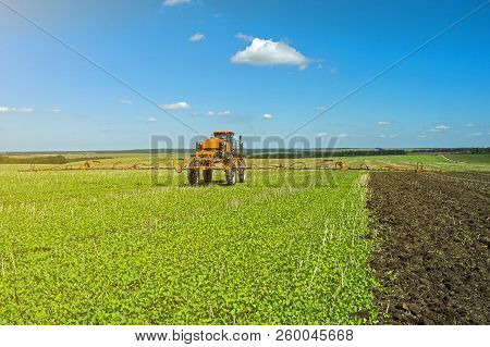 Self-propelled Sprayer Works On A Field Under A Blue Sky With Clouds