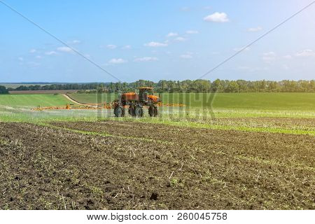 Self-propelled Sprayer Works On A Field Under A Blue Sky With Clouds
