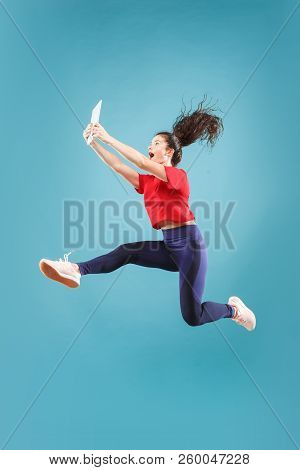 Gadget In Modern Life. Jump Of Young Woman Over Pink Studio Background Using Laptop Or Tablet Gadget