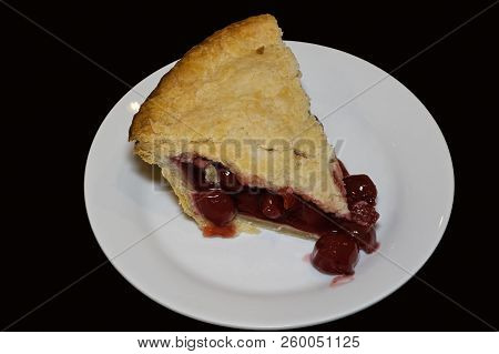 Slice Of Double Crusted Cherry Pie On Black Background. Traditionally, Cherry Pie Is Made With Tart 
