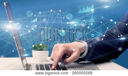 Businessman typing on laptop with linked reports charts grapghs around