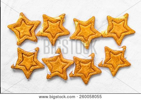 Two Rows Of Eight Decorative Golden Stars Handmade From Dough On A Bright White Fabric Surface