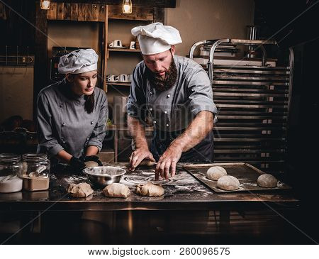Chef Teaching His Assistant To Bake The Bread In A Bakery.