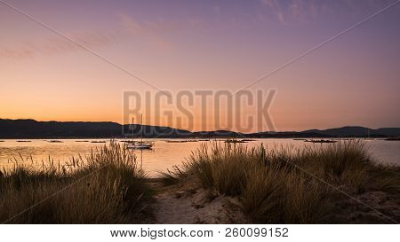 Landscape With A Sailboat Sailing At Sunset On The Shores Of An Island Galicia, Spain
