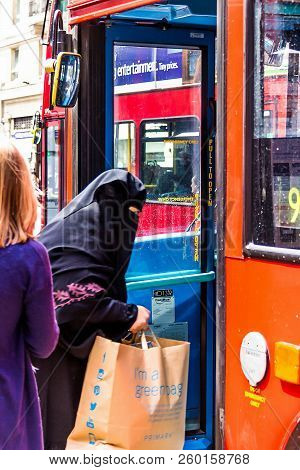London, Uk - June 9, 2015: An Elderly Arab Woman In A Burqa Enters The Bus With Purchases From The P