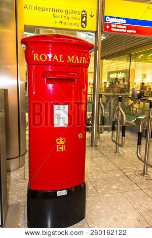 London, Uk - June 9, 2015: Red English Pillar Box Or Post Box In Main Terminal Lounge Of Heathrow Ai