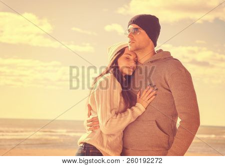 Happy couple enyojing time together on beach during autumn day