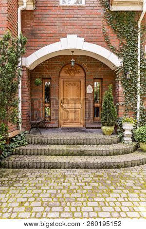 Elegant, Wooden Entrance Door To An Estate With Ivy Growing On Brick Walls
