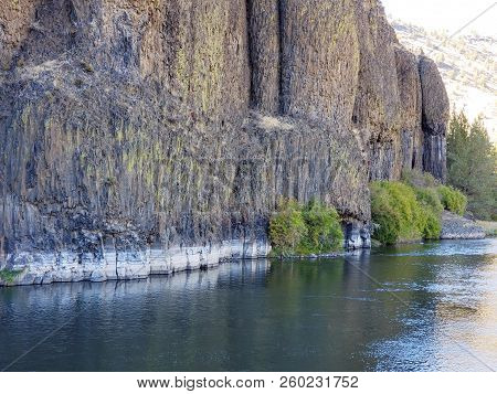 The Beautiful Crooked River With Fall Colored Bushes On Its Banks Flows Through A Canyon Formed From