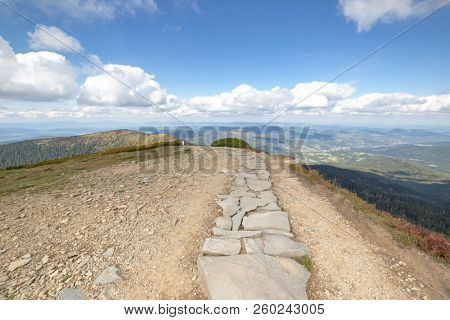 Hiking trail from Babia Gora Mountain to Przelecz Brona Pass in Polish Beskid. High mountains landscape under blue sky with clouds.