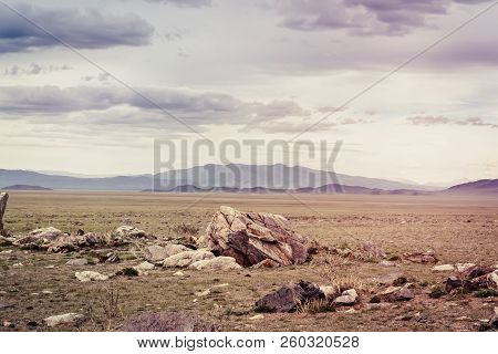 Tarkhatinsky Megalithic Complex. Steppe And Blue Mountains On The Horizon. Altai Russia.
