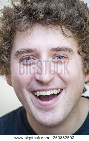 Portrait Of Young Positive Smiling Young Curly Green-eyed Man On White Background.