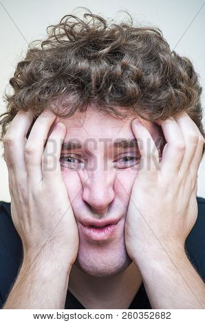 Portrait Of Young Shocked Concentrated Man That Covers His Depressed Face With Two Hands On White Ba