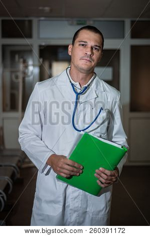 Portrait Of A Beautiful Doctor In The Hospital With A Folder In His Hands