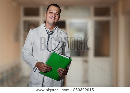 Portrait Of A Beautiful Doctor In The Hospital With A Folder In His Hands