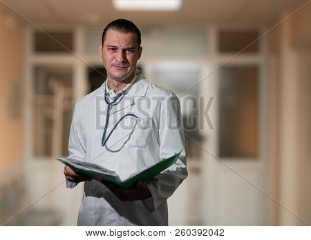 Portrait Of A Beautiful Doctor In The Hospital With A Folder In His Hands