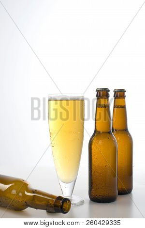Three Brown Beer Bottles And A Glass Of Beer.