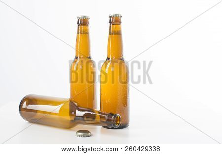 Two Full Brown Beer Bottles And One Empty Resting On Its Side.