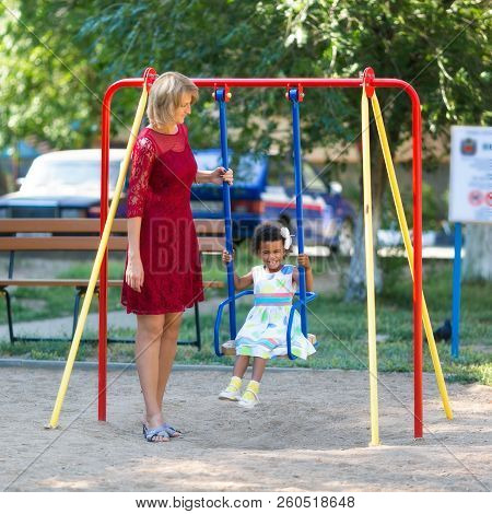 Mom Rolls His Daughter On A Swing.