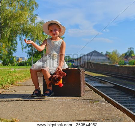 Adorable Little Girl On A Railway Station, Waiting For The Train With Vintage Suitcase. Traveling, H