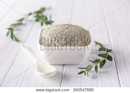 Ceramic Bowl With Green Clay Powder And Fresh Eucalyptus Leaves On White Background. Concept Of Face