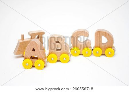 Wooden Letters A, B, C, D Of A Train Alphabet And Locomotive With Yellow Wheels On White Background.