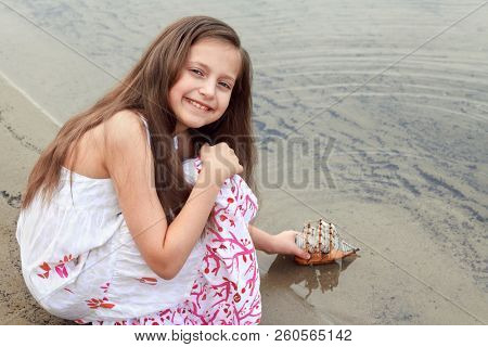 girl playing with a toy sailing ship by the river