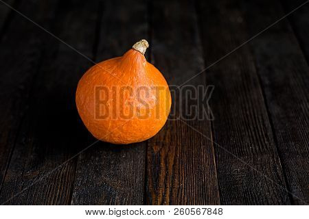 Small Orange Pumpkins On The Dark Wooden Table, Autumn Concept, Harrvest Time. Copy Space.