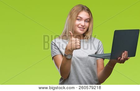 Young caucasian woman using computer laptop over isolated background happy with big smile doing ok sign, thumb up with fingers, excellent sign