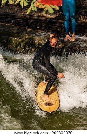 Munich, Germany - Sept 8, 2018: A Man Surfing In The Waves Of The Eisbach River In Downtown Of Munic