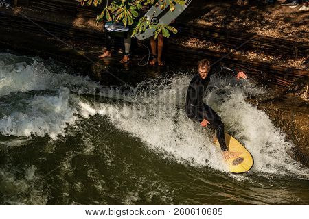 Munich, Germany - Sept 8, 2018: A Man Surfing In The Waves Of The Eisbach River In Downtown Of Munic