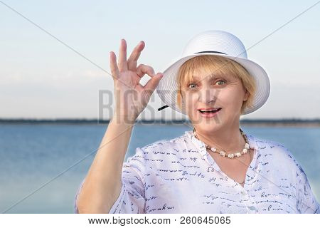 Happy Retired Elderly Woman In White Hat Shows Okey Geste