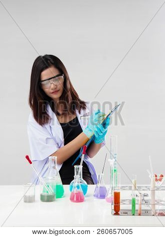 The Chemist In Protective Eyeglasses Working By Test Tube With Reagent In Lab,she Is Writing The Res