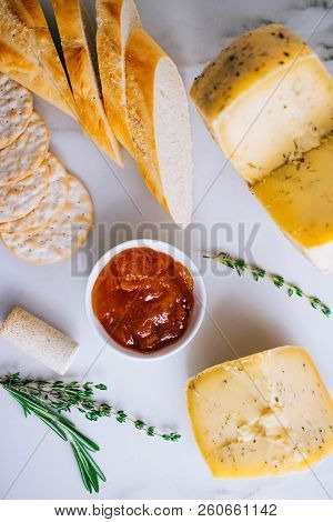 Cachotta Cheese With Herbs, Jam, Baguette, Crackers, Rosemary And Thyme On Marble