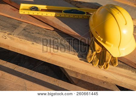Abstract of Constrcution Hard Hat, Gloves and Level Resting on Wood Planks.