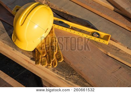 Abstract of Constrcution Hard Hat, Gloves and Level Resting on Wood Planks.