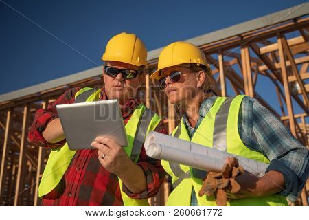 Male and Female Construciton Workers Using Computer Pad at Construciton Site.