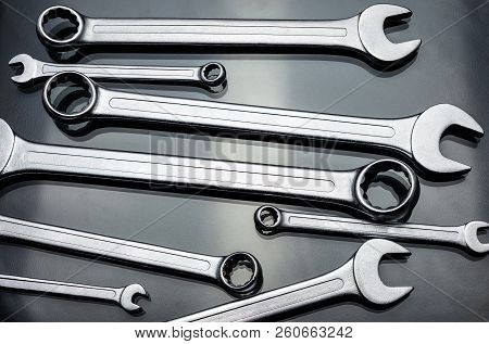 Metal Flat Wrenches Lying On A Black, Shiny Table, Flat View From Above.