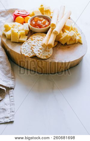 Cheese Board With Tomatoes, Jam, Baguette, Bread Sticks And Crackers