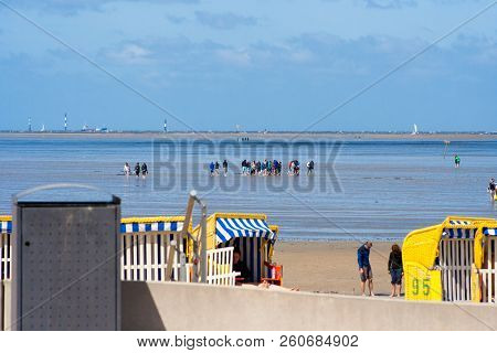 People Walking On The Beach In Cuxhaven At Low Tide. People In The Water On The North Sea - 07/07/20