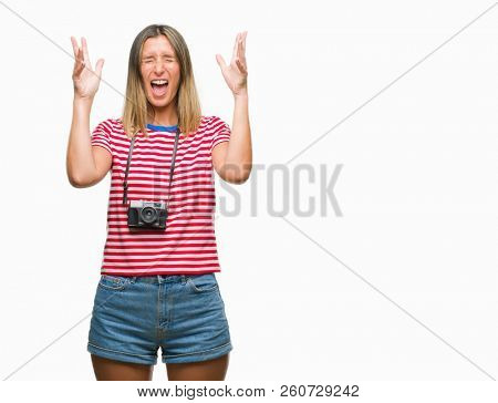 Young beautiful woman taking pictures using vintage photo camera over isolated background celebrating mad and crazy for success with arms raised and closed eyes screaming excited. Winner concept