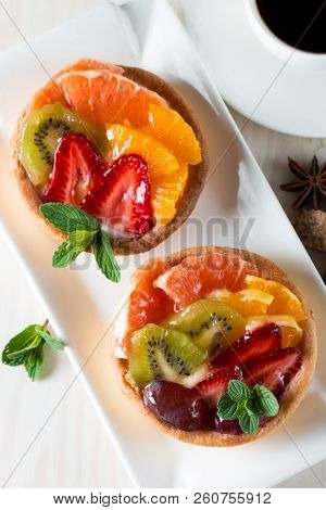 Fresh Fruit And Berry Tart Dessert With Toss Sugar On Wooden Background. Delicious Sweet Cake With R