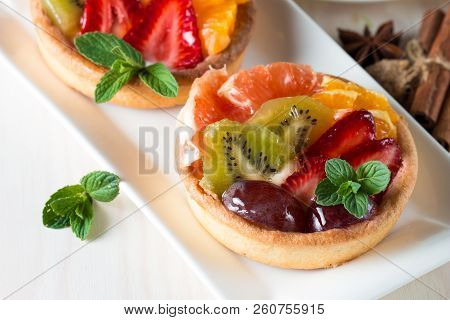 Fresh Fruit And Berry Tart Dessert With Toss Sugar On Wooden Background. Delicious Sweet Cake With R