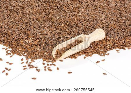 Lot Of Whole Fresh Brown Flaxseeds With Wooden Scoop Isolated On White Background