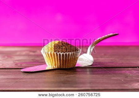 One Whole Fresh Baked Marble Muffin On Silver Cake Server With Pink In Background