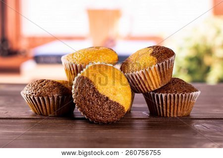 Group Of Five Whole Fresh Baked Marble Muffin With Books Near The Window In Background