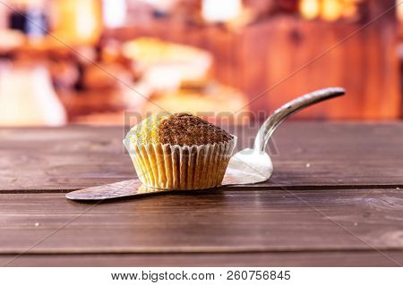 One Whole Fresh Baked Marble Muffin On Silver Cake Server With Rustic Wood Kitchen In Background