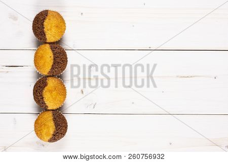 Group Of Four Whole Fresh Baked Marble Muffin Flatlay On White Wood