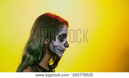 Halloween, Girl With Make-up Skeleton On Half Face, Dressed As Witch, Posing On Bright Yellow Backgr
