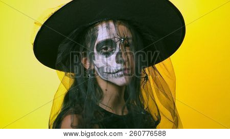 Halloween, Girl With Make-up Skeleton On Half Face, Dressed As Witch, Posing On Bright Yellow Backgr